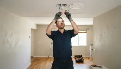 Electrician installing a ceiling light fixture in a Stockton, CA home