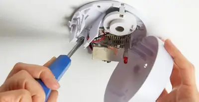Certified technician wiring smoke detector during installation in Stockton, CA